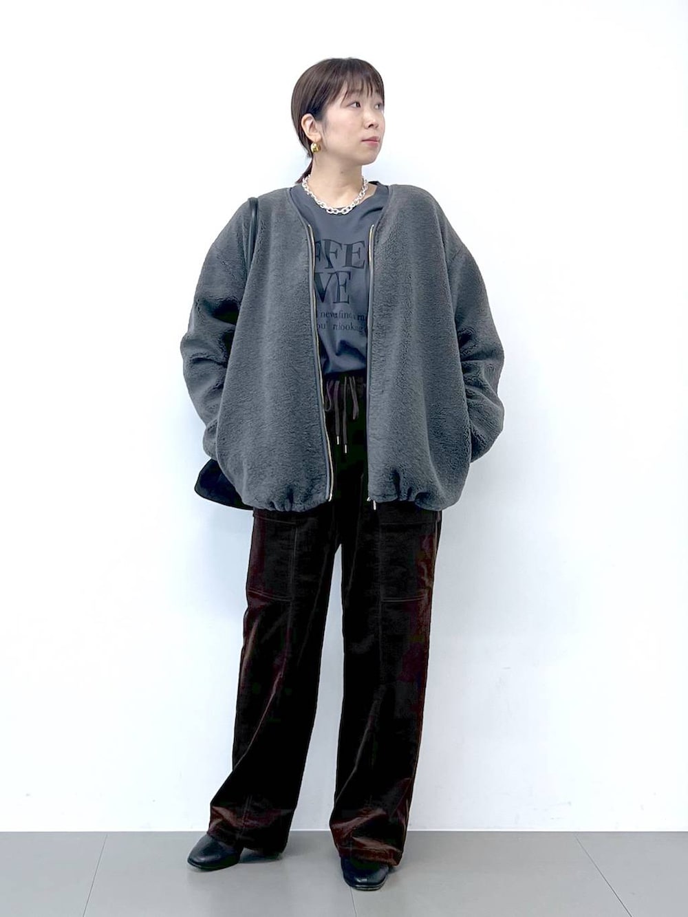 ブラック系のブーツ、グレー系のブルゾン、シルバー系のネックレスを着用したレディースの秋コーディネートの3枚目の写真