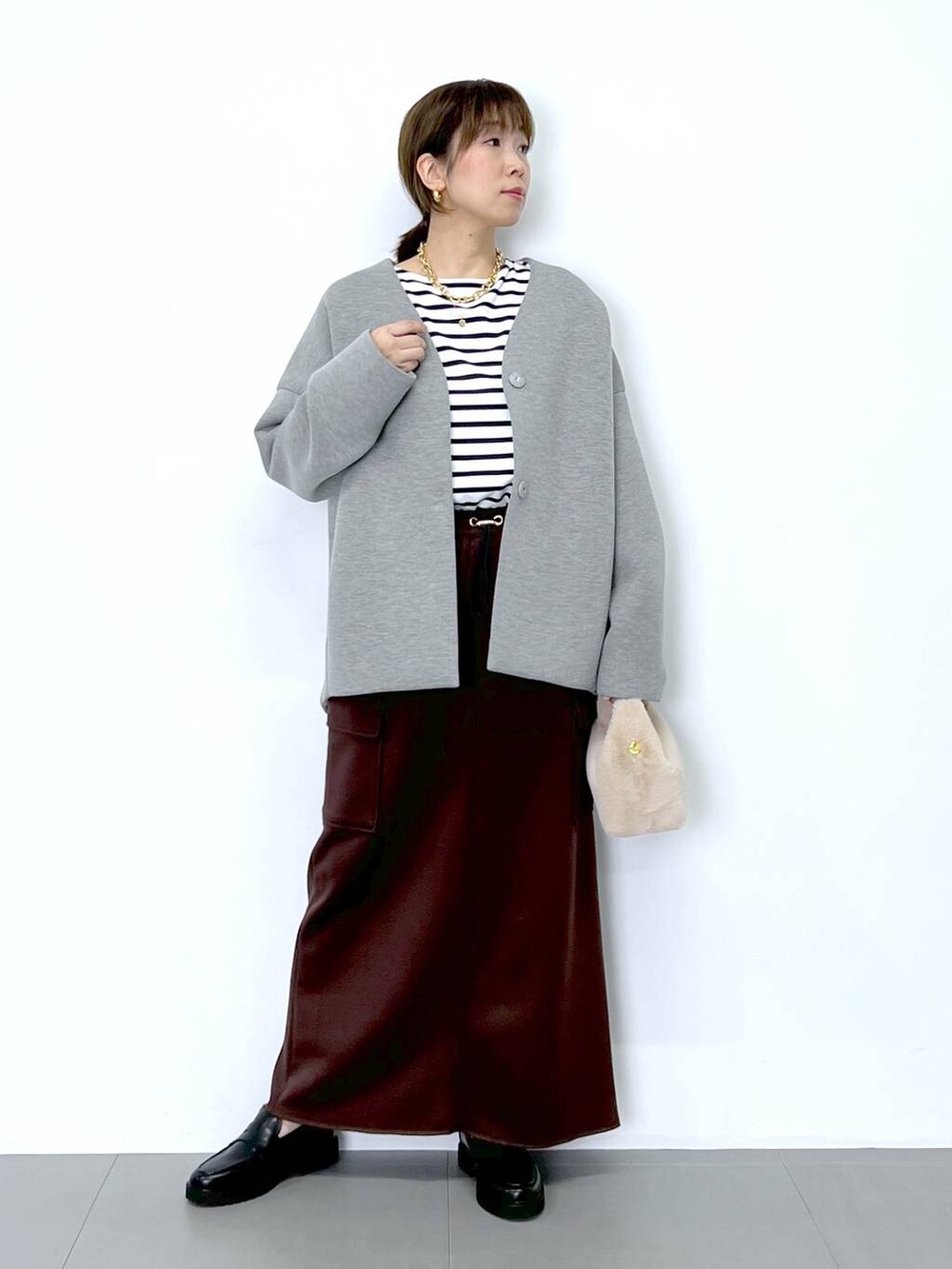 ブラウン系のスカート、ホワイト系のショルダーバッグ、ホワイト系のTシャツ/カットソーを着用したレディースの秋コーディネートの6枚目の写真