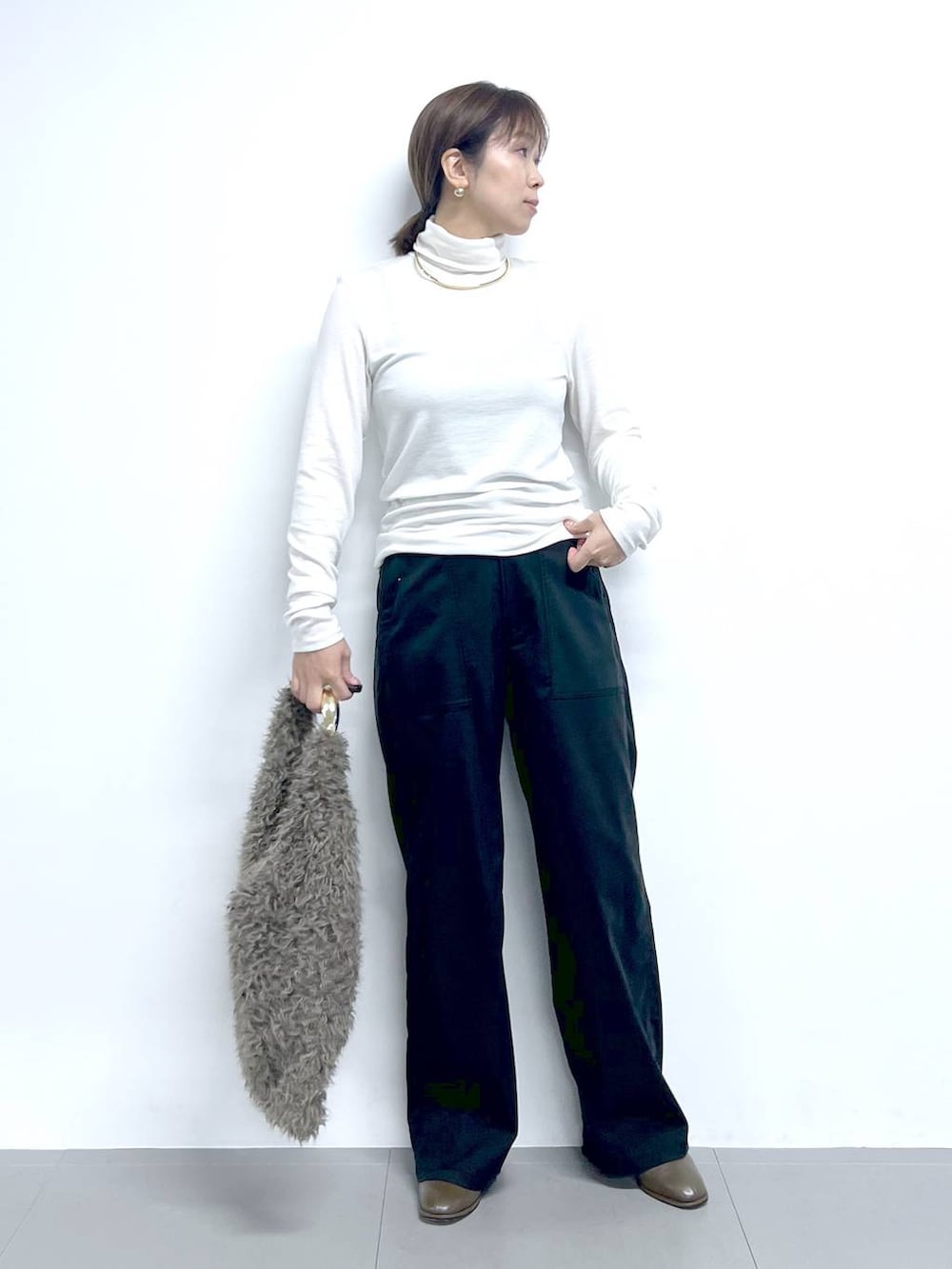 ブラック系のチノパンツ、ホワイト系のTシャツ/カットソー、ブラウン系のハンドバッグを着用したレディースの秋コーディネートの3枚目の写真