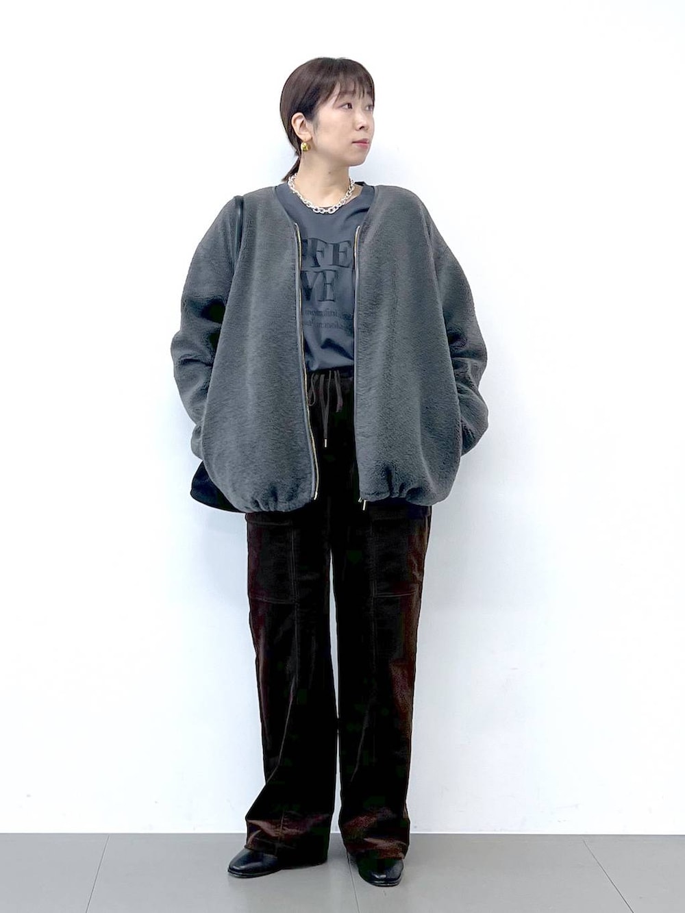 ブラック系のブーツ、グレー系のブルゾン、シルバー系のネックレスを着用したレディースの秋コーディネートの2枚目の写真