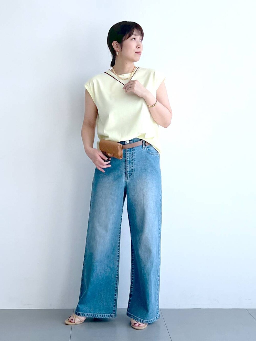 ブルー系のデニムパンツ、イエロー系のTシャツ/カットソー、ベージュ系のショルダーバッグを着用したレディースの春コーディネートの6枚目の写真