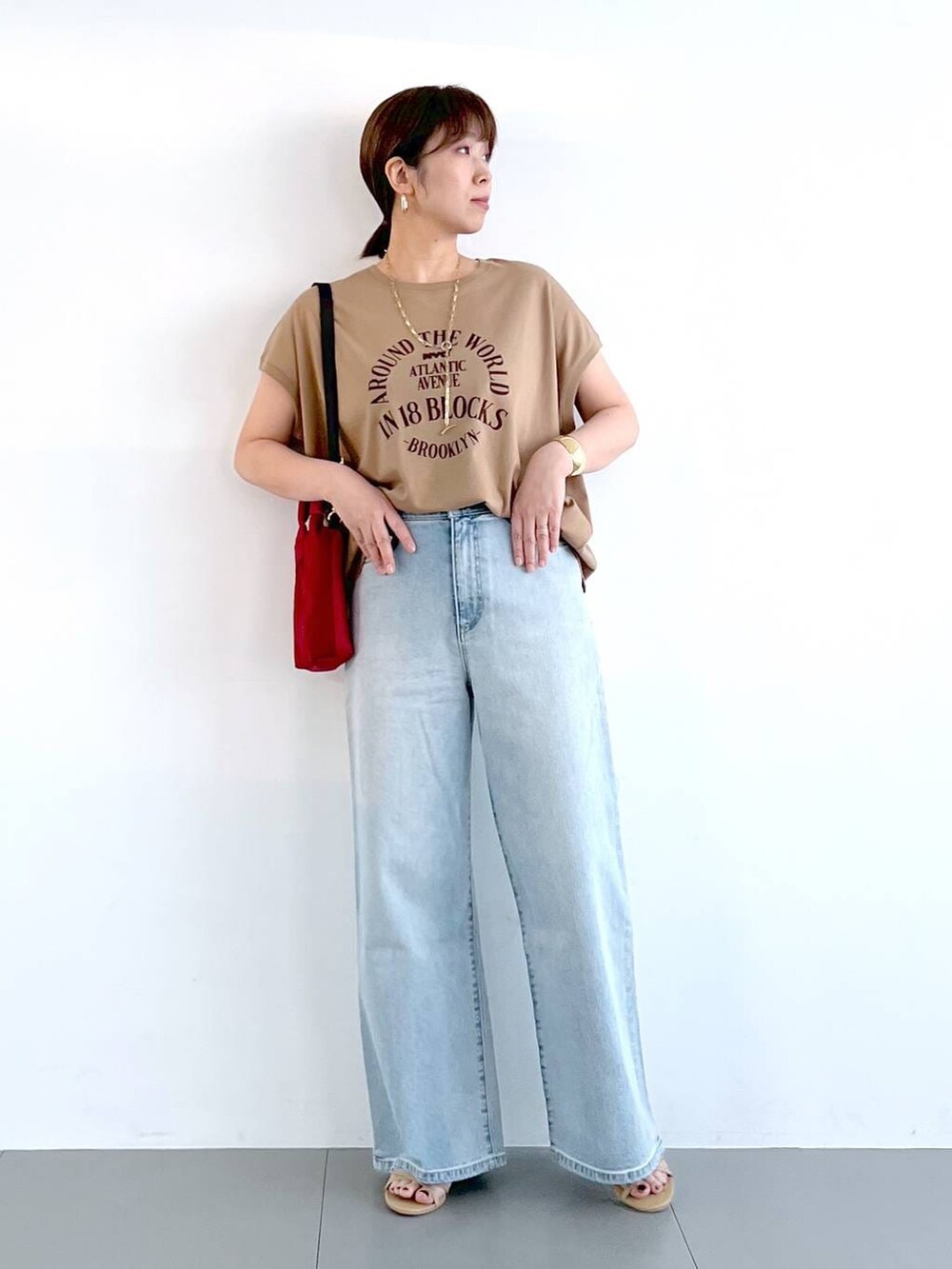 ブルー系のデニムパンツ、ベージュ系のサンダル、ゴールド系のネックレスを着用したレディースの春コーディネートの2枚目の写真