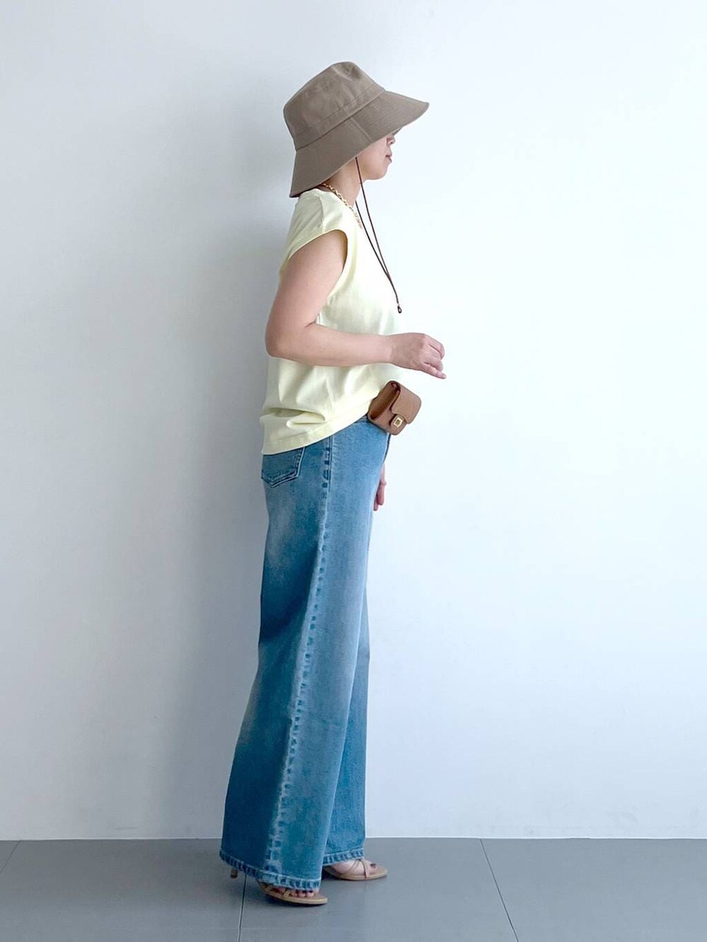 ブルー系のデニムパンツ、イエロー系のTシャツ/カットソー、ベージュ系のショルダーバッグを着用したレディースの春コーディネートの8枚目の写真