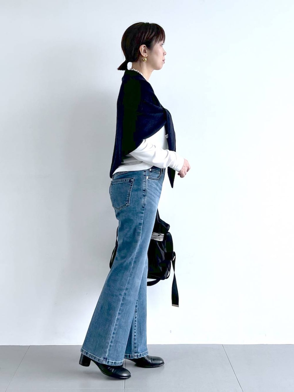 ブルー系のデニムパンツ、その他のショルダーバッグ、ブラック系のブーツを着用したレディースの秋コーディネートの5枚目の写真