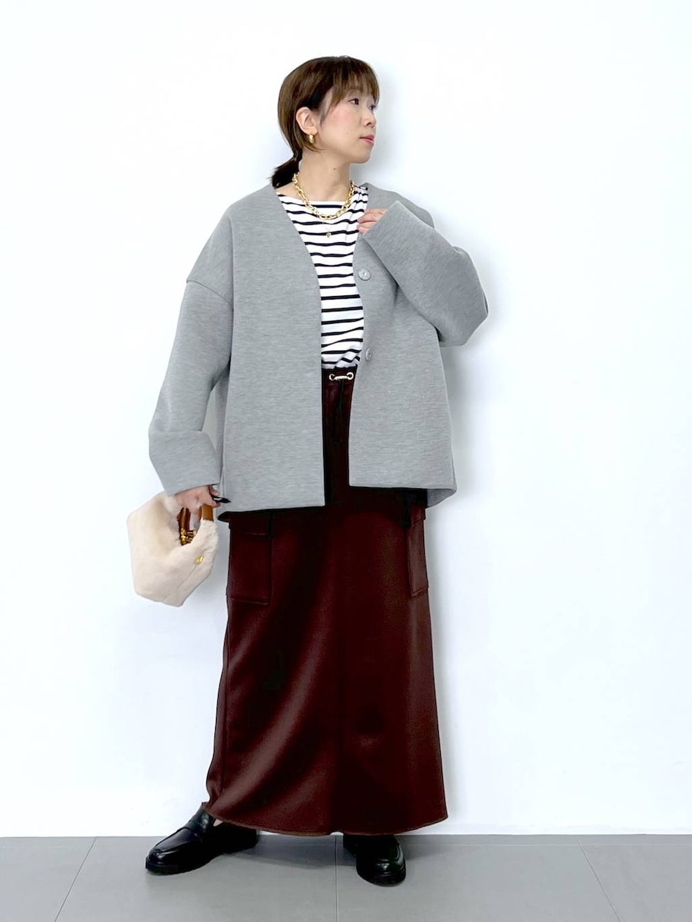 ブラウン系のスカート、ホワイト系のショルダーバッグ、ホワイト系のTシャツ/カットソーを着用したレディースの秋コーディネートの4枚目の写真