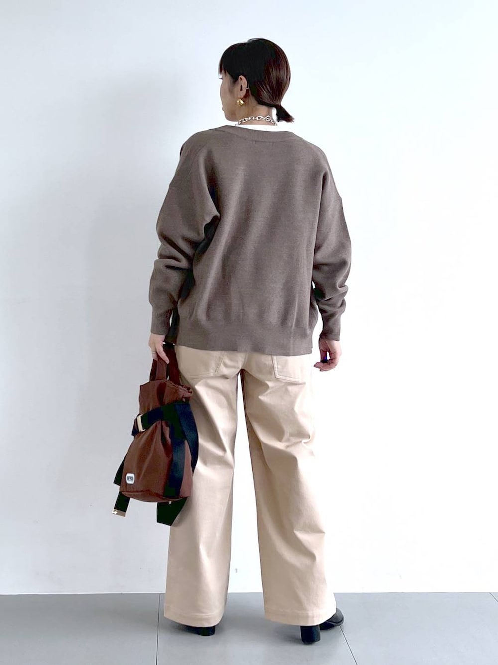 ブラウン系のショルダーバッグ、ホワイト系のTシャツ/カットソー、ブラック系のブーツを着用したレディースの秋コーディネートの6枚目の写真