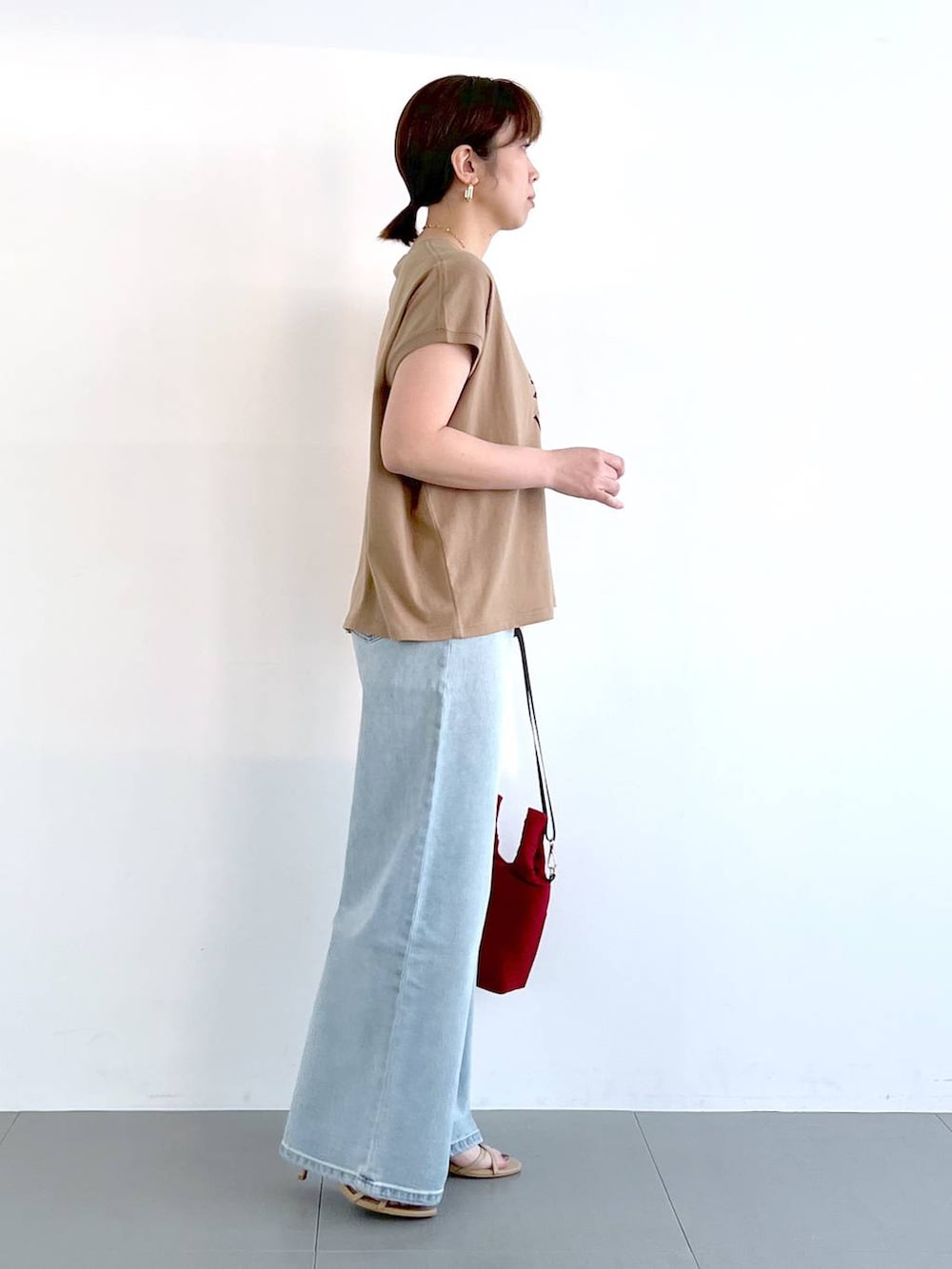 ブルー系のデニムパンツ、ベージュ系のサンダル、ゴールド系のネックレスを着用したレディースの春コーディネートの8枚目の写真