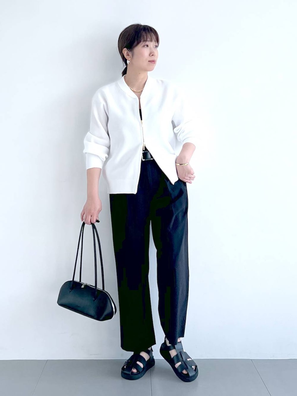 ブラック系のその他パンツ、ブラック系のハンドバッグ、ホワイト系のカーディガン/ボレロを着用したレディースの春コーディネートの4枚目の写真