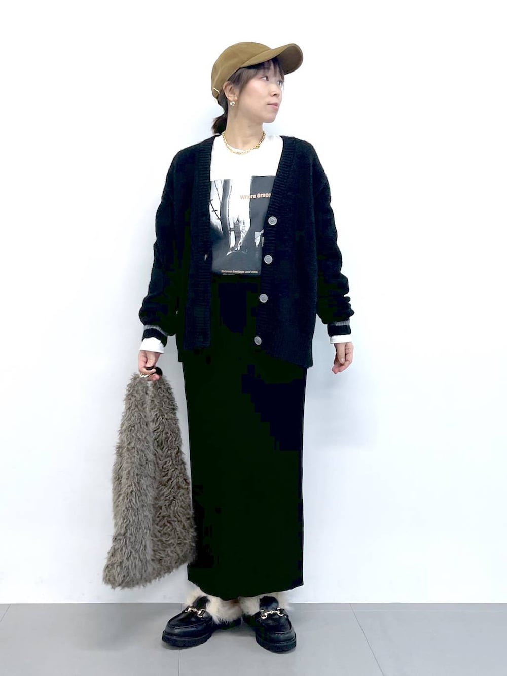 ブラック系のスカート、ブラック系のカーディガン/ボレロ、ブラウン系のハンドバッグを着用したレディースの秋コーディネートの6枚目の写真