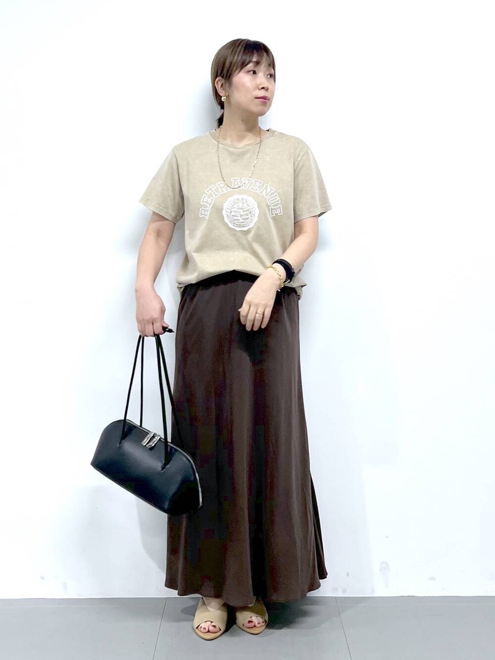 ブラック系のトートバッグ、ベージュ系のサンダル、ベージュ系のTシャツ/カットソーを着用したレディースの夏コーディネートの5枚目の写真