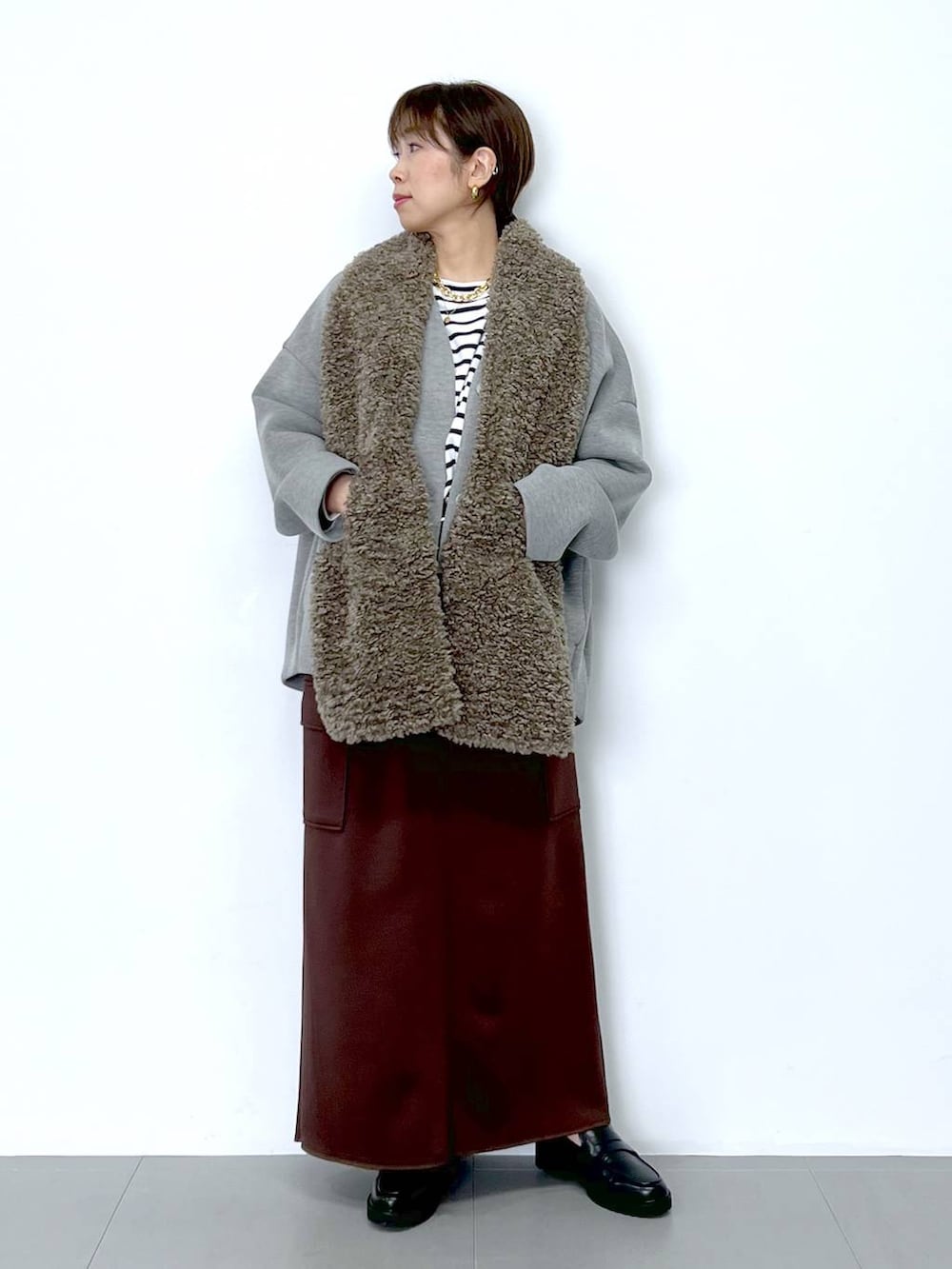 ブラウン系のスカート、ホワイト系のショルダーバッグ、ホワイト系のTシャツ/カットソーを着用したレディースの秋コーディネートの2枚目の写真