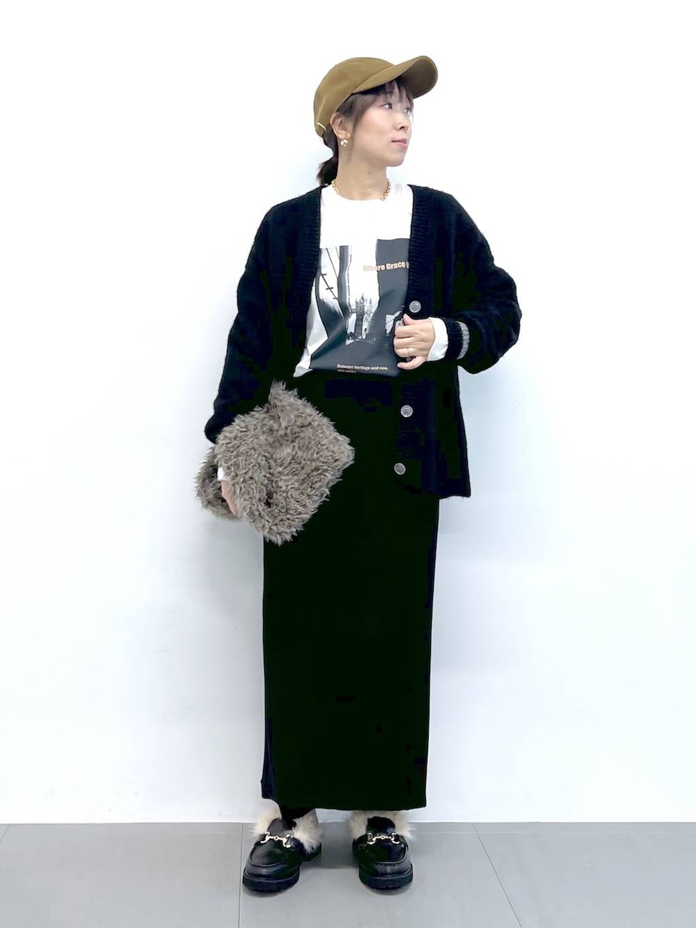 ブラック系のスカート、ブラック系のカーディガン/ボレロ、ブラウン系のハンドバッグを着用したレディースの秋コーディネートの7枚目の写真