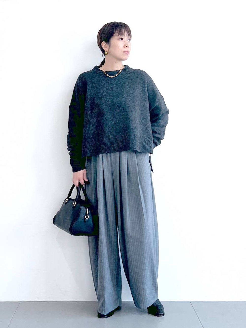 ブラック系のボストンバッグ、ブラック系のブーツ、グレー系のニット/セーターを着用したレディースの秋コーディネートの5枚目の写真