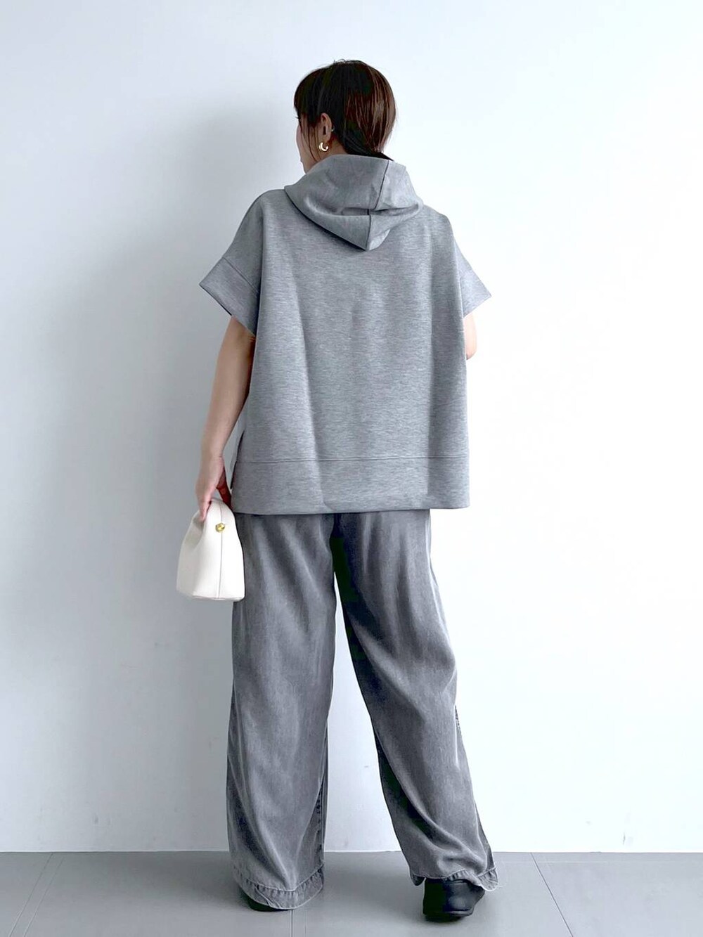 グレー系のパーカー、ブラック系のサンダル、ホワイト系のハンドバッグを着用したレディースの夏コーディネートの8枚目の写真