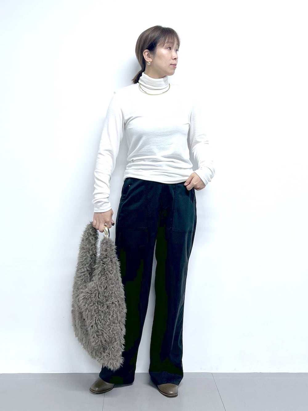 ブラック系のチノパンツ、ホワイト系のTシャツ/カットソー、ブラウン系のハンドバッグを着用したレディースの秋コーディネートの2枚目の写真