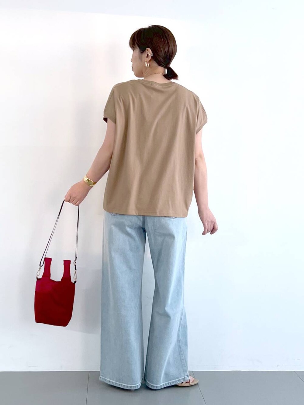 ブルー系のデニムパンツ、ベージュ系のサンダル、ゴールド系のネックレスを着用したレディースの春コーディネートの9枚目の写真