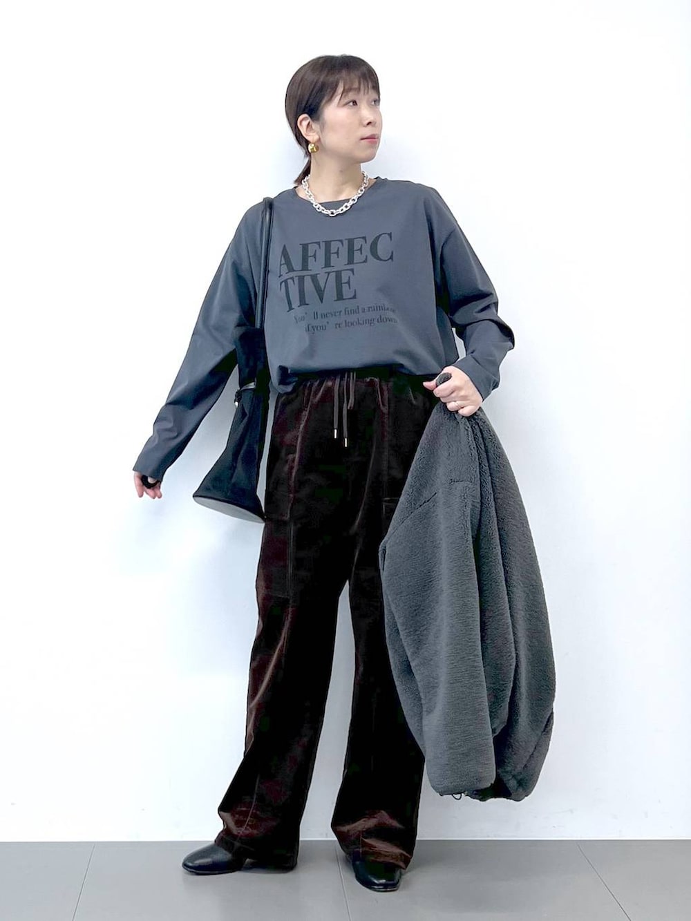 ブラック系のブーツ、グレー系のブルゾン、シルバー系のネックレスを着用したレディースの秋コーディネートの9枚目の写真