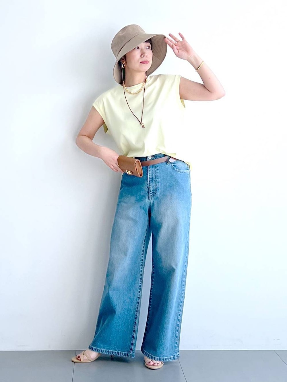 ブルー系のデニムパンツ、イエロー系のTシャツ/カットソー、ベージュ系のショルダーバッグを着用したレディースの春コーディネートの4枚目の写真