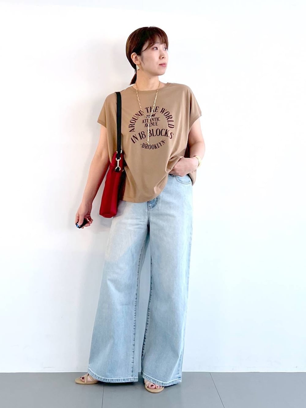 ブルー系のデニムパンツ、ベージュ系のサンダル、ゴールド系のネックレスを着用したレディースの春コーディネートの6枚目の写真