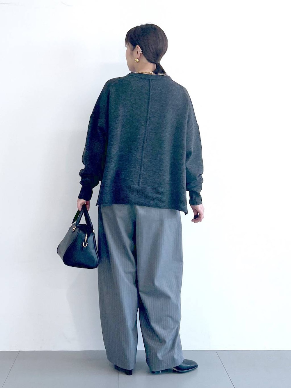 ブラック系のボストンバッグ、ブラック系のブーツ、グレー系のニット/セーターを着用したレディースの秋コーディネートの8枚目の写真