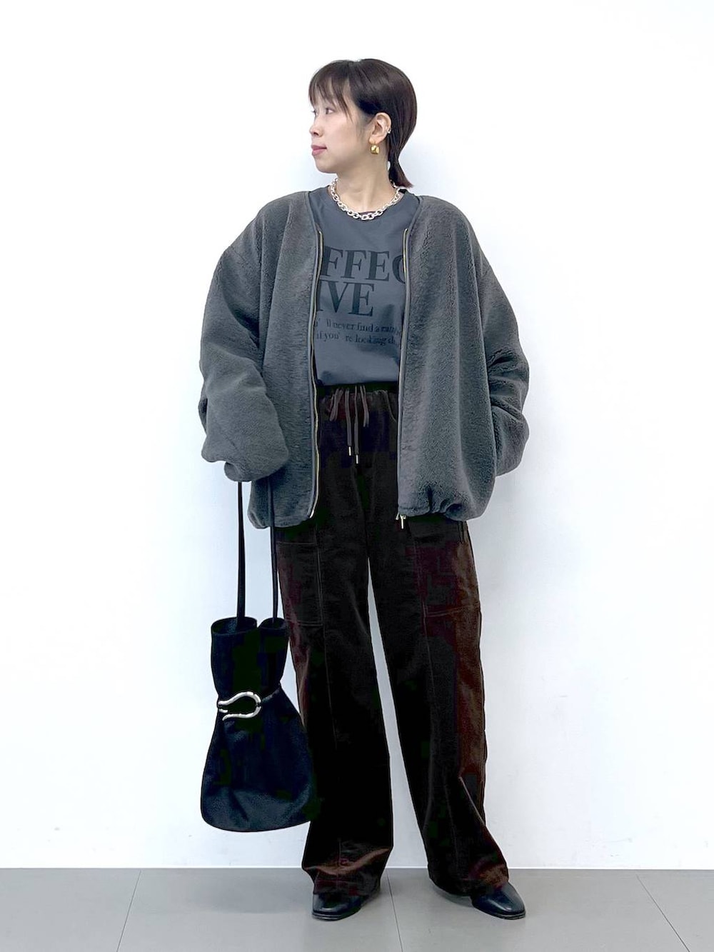 ブラック系のブーツ、グレー系のブルゾン、シルバー系のネックレスを着用したレディースの秋コーディネートの4枚目の写真