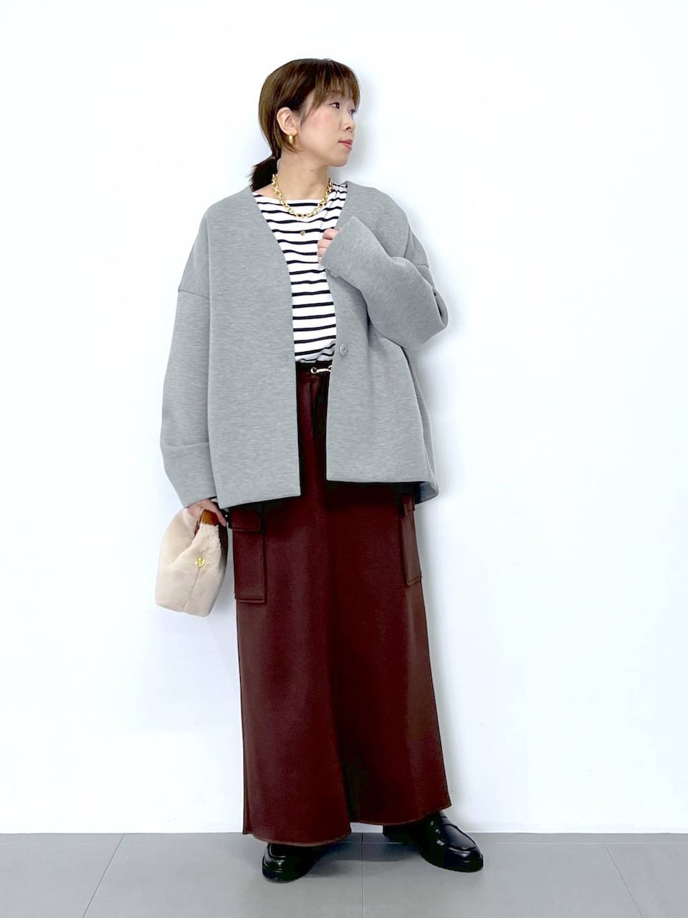 ブラウン系のスカート、ホワイト系のショルダーバッグ、ホワイト系のTシャツ/カットソーを着用したレディースの秋コーディネートの5枚目の写真