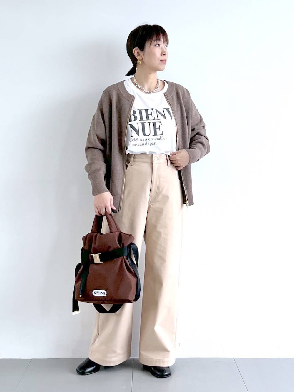 ブラウン系のショルダーバッグ、ホワイト系のTシャツ/カットソー、ブラック系のブーツを着用したレディースの秋コーディネートの3枚目の写真