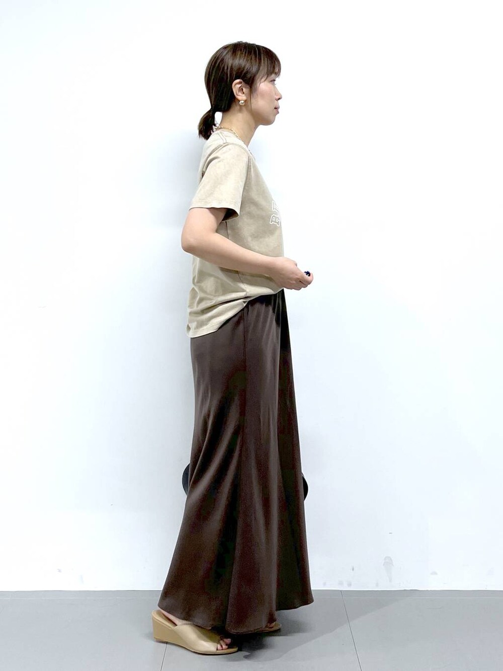 ブラック系のトートバッグ、ベージュ系のサンダル、ベージュ系のTシャツ/カットソーを着用したレディースの夏コーディネートの6枚目の写真