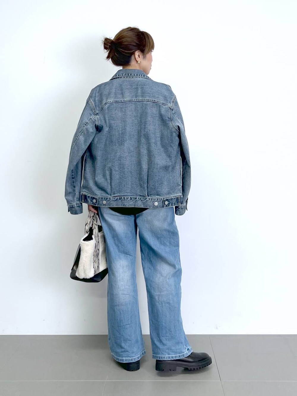 ブルー系のデニムパンツ、ブラック系のTシャツ/カットソー、ブラック系のブーツを着用したレディースの秋コーディネートの6枚目の写真