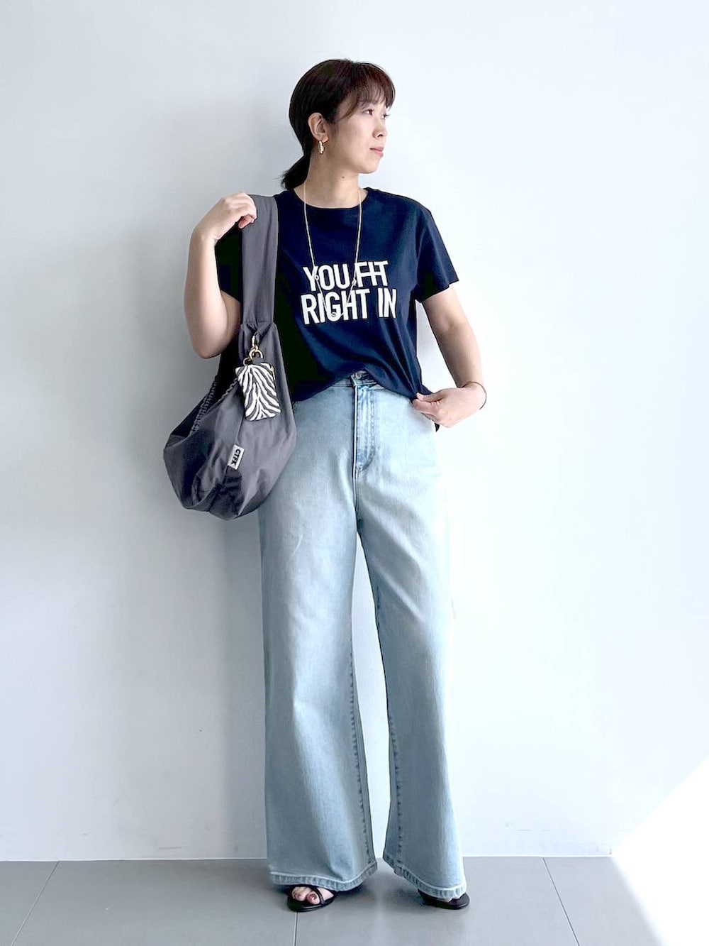 ブルー系のデニムパンツ、グレー系のショルダーバッグ、ブラック系のサンダルを着用したレディースの夏コーディネートの3枚目の写真