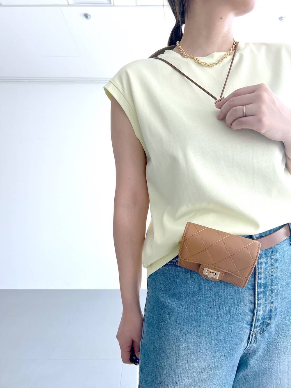 ブルー系のデニムパンツ、イエロー系のTシャツ/カットソー、ベージュ系のショルダーバッグを着用したレディースの春コーディネートの5枚目の写真