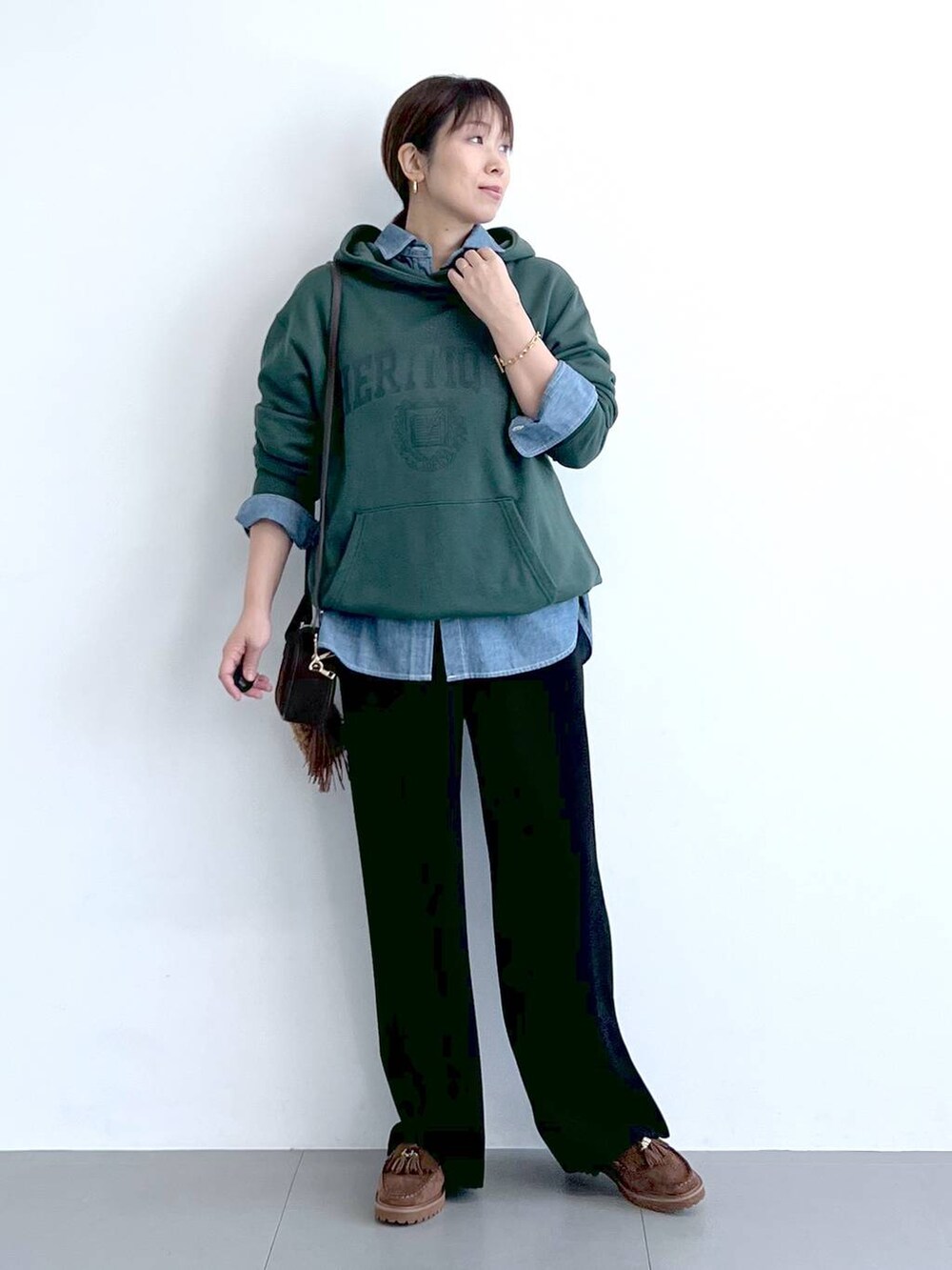 ブラック系のスラックス、グリーン系のパーカー、ブラウン系のショルダーバッグを着用したレディースの秋コーディネートの7枚目の写真