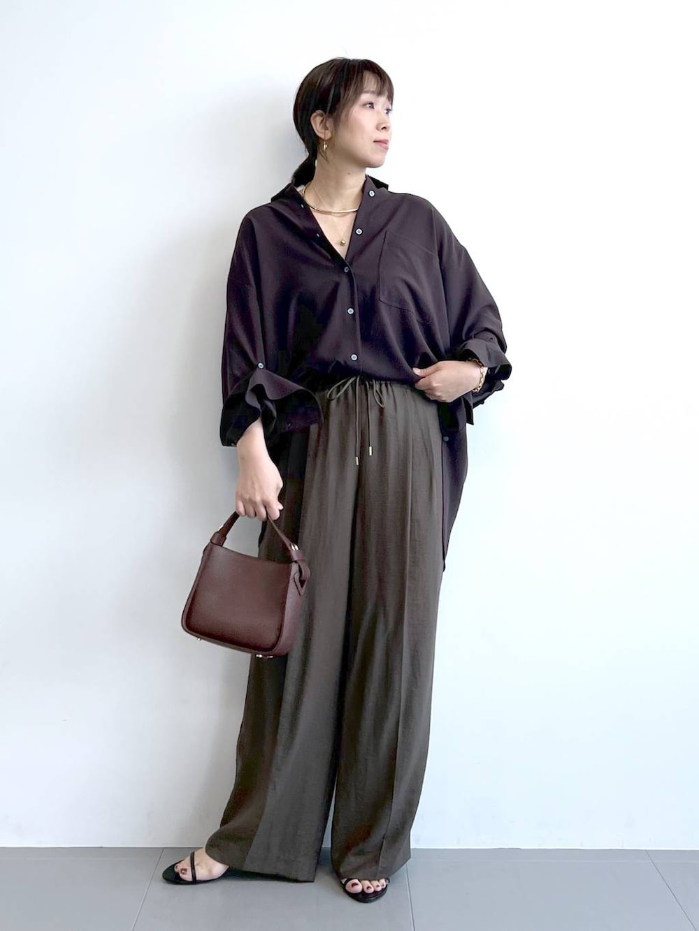 ブラウン系のハンドバッグ、ブラック系のサンダル、ブラウン系のシャツ/ブラウスを着用したレディースの夏コーディネートの5枚目の写真