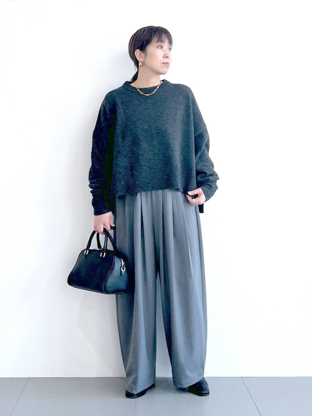 ブラック系のボストンバッグ、ブラック系のブーツ、グレー系のニット/セーターを着用したレディースの秋コーディネートの6枚目の写真