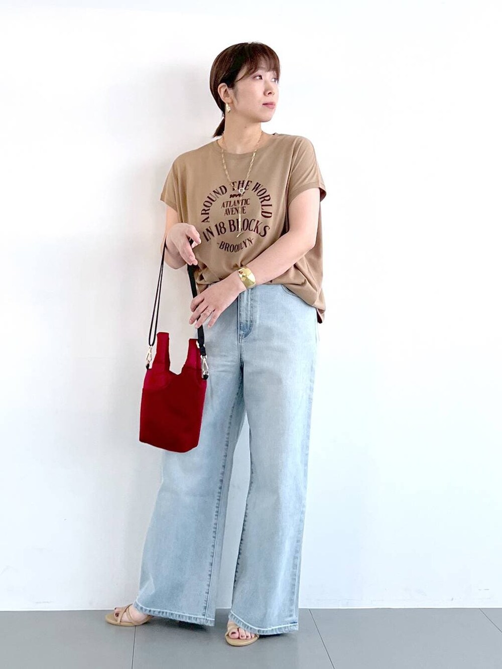 ブルー系のデニムパンツ、ベージュ系のサンダル、ゴールド系のネックレスを着用したレディースの春コーディネートの5枚目の写真