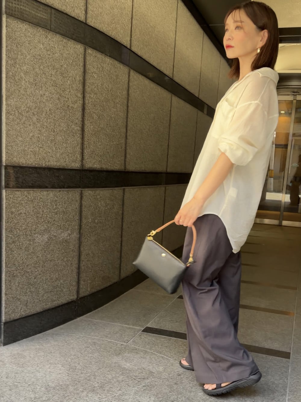 ブラック系のショルダーバッグ、グレー系のスラックス、ホワイト系のシャツ/ブラウスを着用したレディースの夏コーディネートの5枚目の写真