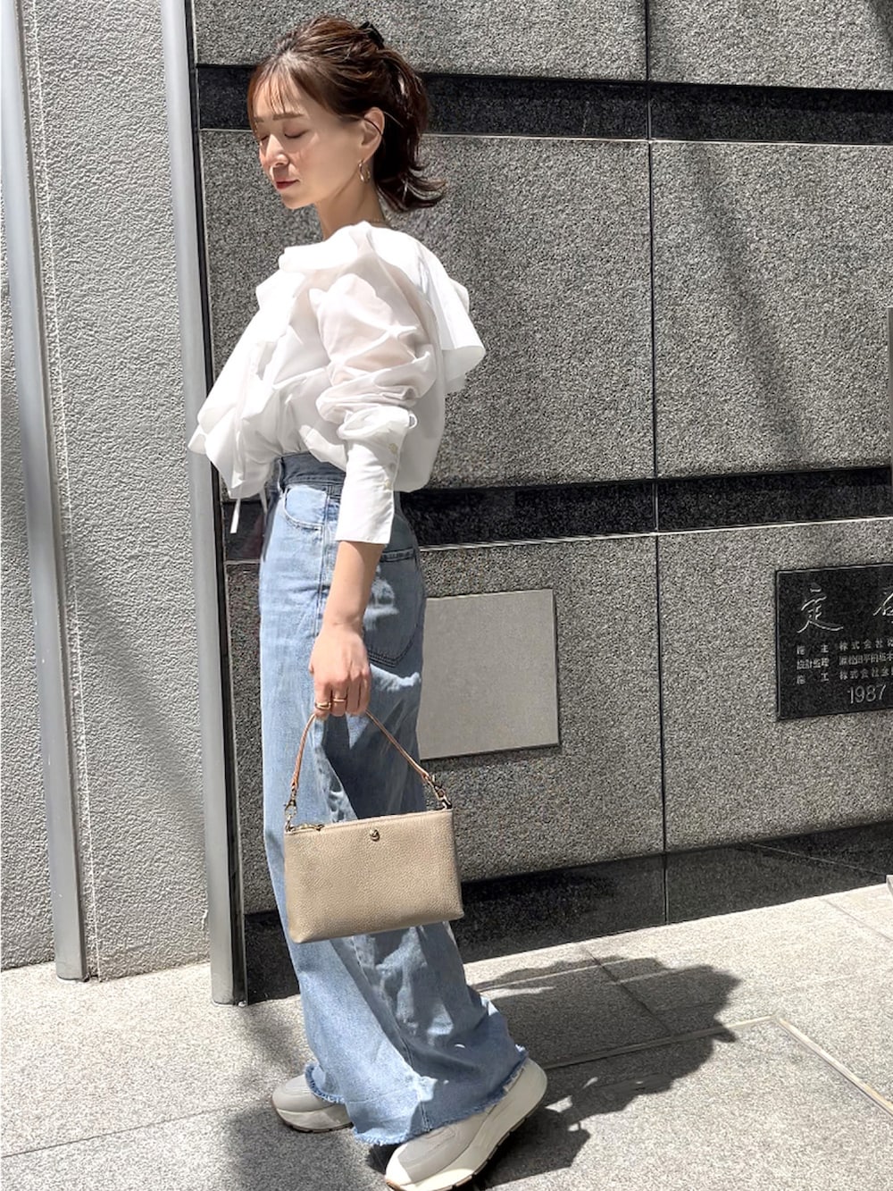 グレー系のショルダーバッグ、ホワイト系のシャツ/ブラウス、グレー系のデニムパンツを着用したレディースの春コーディネートの5枚目の写真