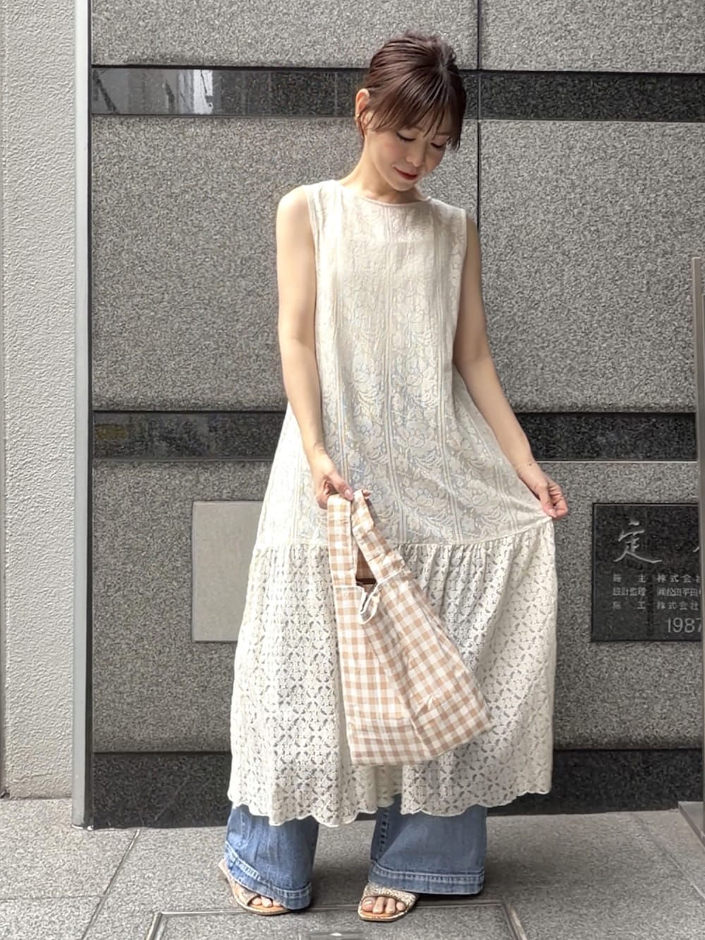 ベージュ系のワンピース、ベージュ系のエコバッグ/サブバッグ、ブルー系のデニムパンツを着用したレディースの夏コーディネートの3枚目の写真