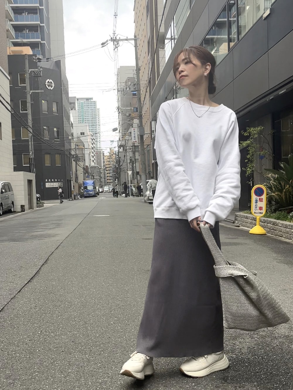 シルバー系のハンドバッグ、グレー系のスカート、ホワイト系のスニーカーを着用したレディースの春コーディネートの5枚目の写真