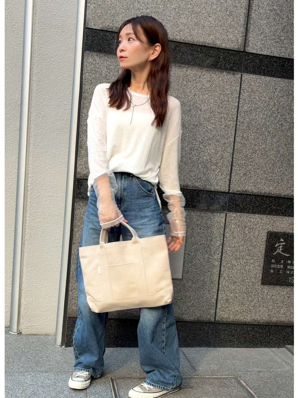 ホワイト系のTシャツ/カットソー、ホワイト系のトートバッグ、ブルー系のデニムパンツを着用したレディースの秋コーディネートの4枚目の写真