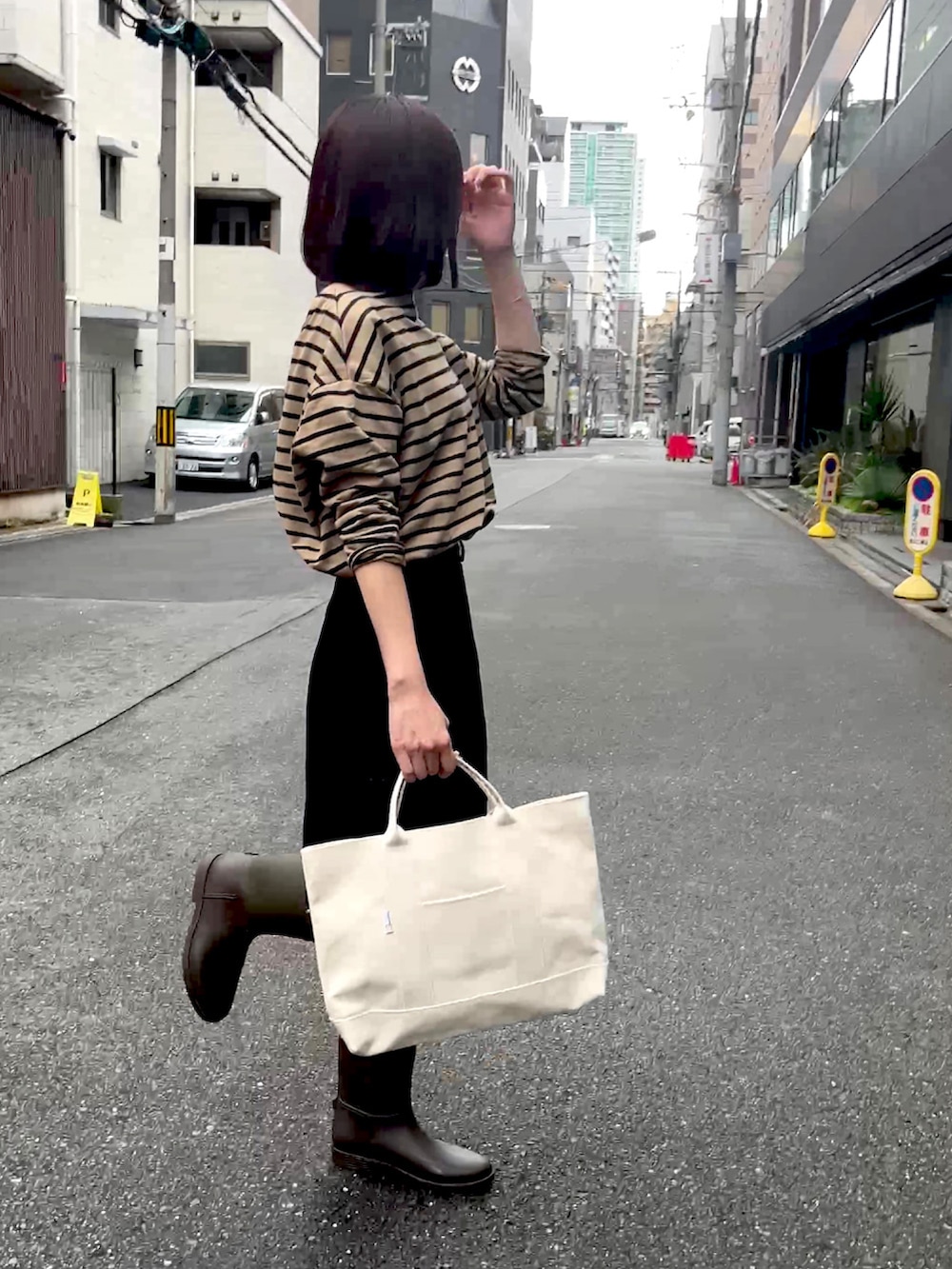 ブラック系のトートバッグ、ベージュ系のTシャツ/カットソー、グレー系のレインシューズを着用したレディースの春コーディネートの2枚目の写真