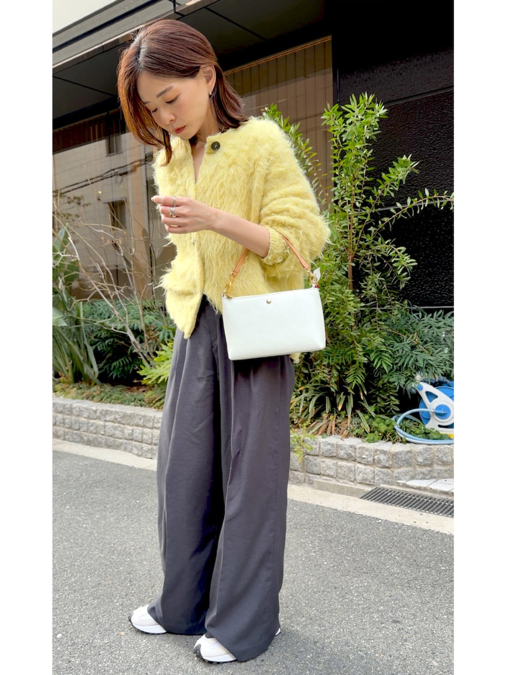 イエロー系のカーディガン/ボレロ、レッド系のハンドバッグ、グレー系のスラックスを着用したレディースの冬コーディネートの4枚目の写真