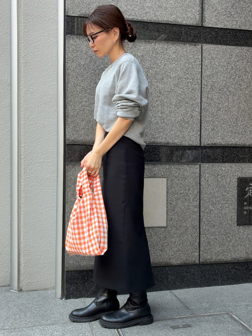 グレー系のスウェット、オレンジ系のエコバッグ/サブバッグ、ブラック系のスカートを着用したレディースの秋コーディネートの2枚目の写真