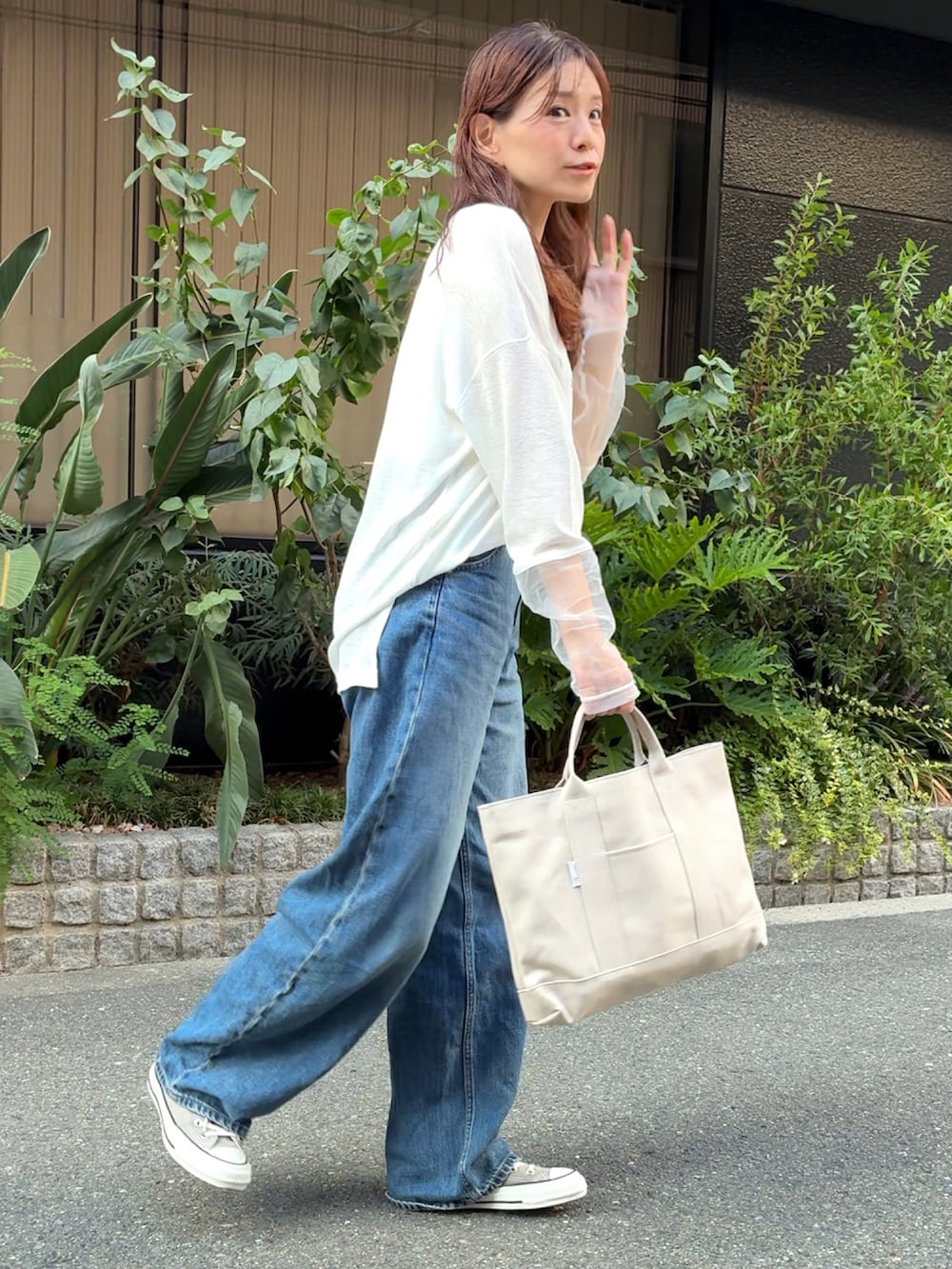 ホワイト系のTシャツ/カットソー、ホワイト系のトートバッグ、ブルー系のデニムパンツを着用したレディースの秋コーディネートの3枚目の写真