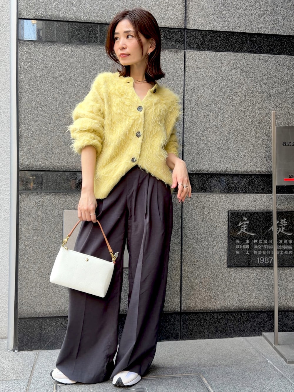 イエロー系のカーディガン/ボレロ、レッド系のハンドバッグ、グレー系のスラックスを着用したレディースの冬コーディネートの3枚目の写真