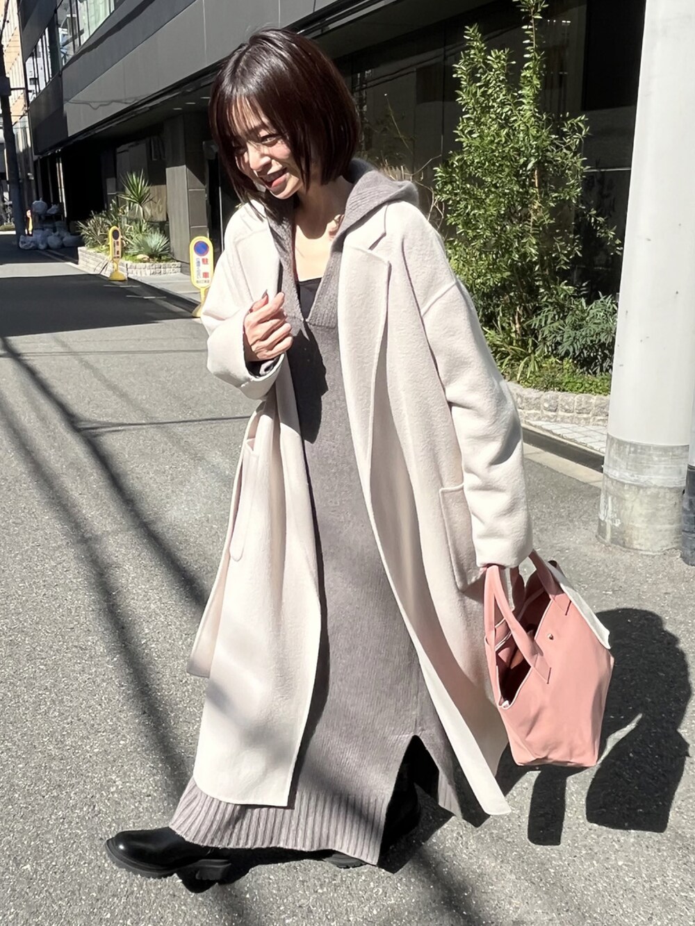 ピンク系のトートバッグ、ホワイト系のチェスターコート、グレー系のワンピースを着用したレディースの冬コーディネートの4枚目の写真