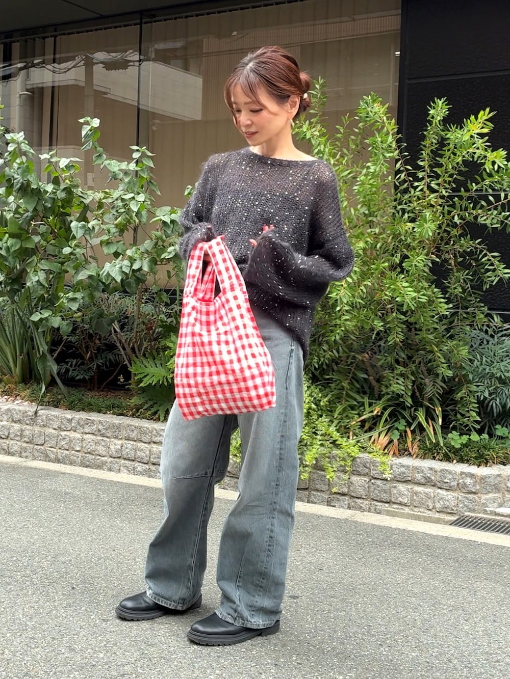 ブラック系のニット/セーター、ブルー系のデニムパンツ、レッド系のエコバッグ/サブバッグを着用したレディースの秋コーディネートの2枚目の写真