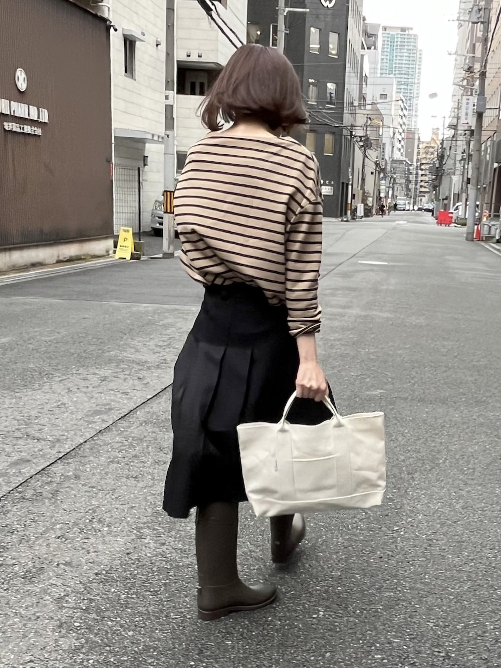 ブラック系のトートバッグ、ベージュ系のTシャツ/カットソー、グレー系のレインシューズを着用したレディースの春コーディネートの3枚目の写真
