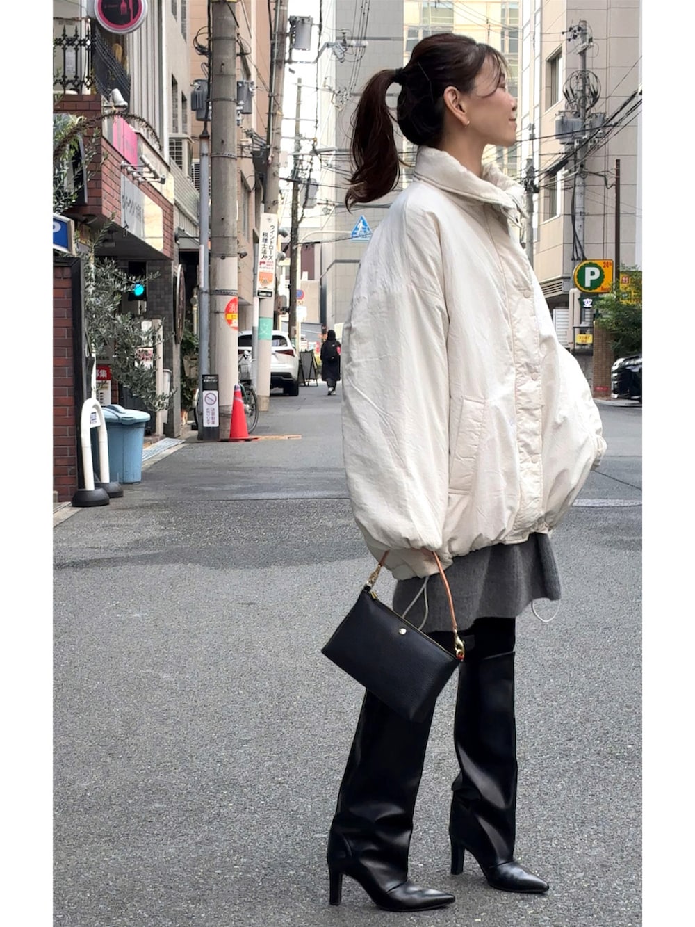 ホワイト系のブルゾン、ブラック系のショルダーバッグ、ブラック系のブーツを着用したレディースの冬コーディネートの3枚目の写真