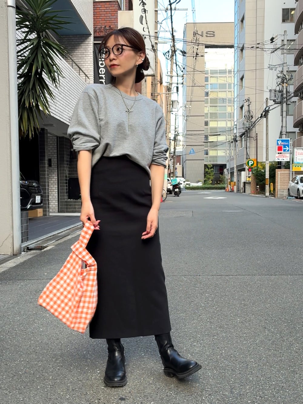グレー系のスウェット、オレンジ系のエコバッグ/サブバッグ、ブラック系のスカートを着用したレディースの秋コーディネートの3枚目の写真
